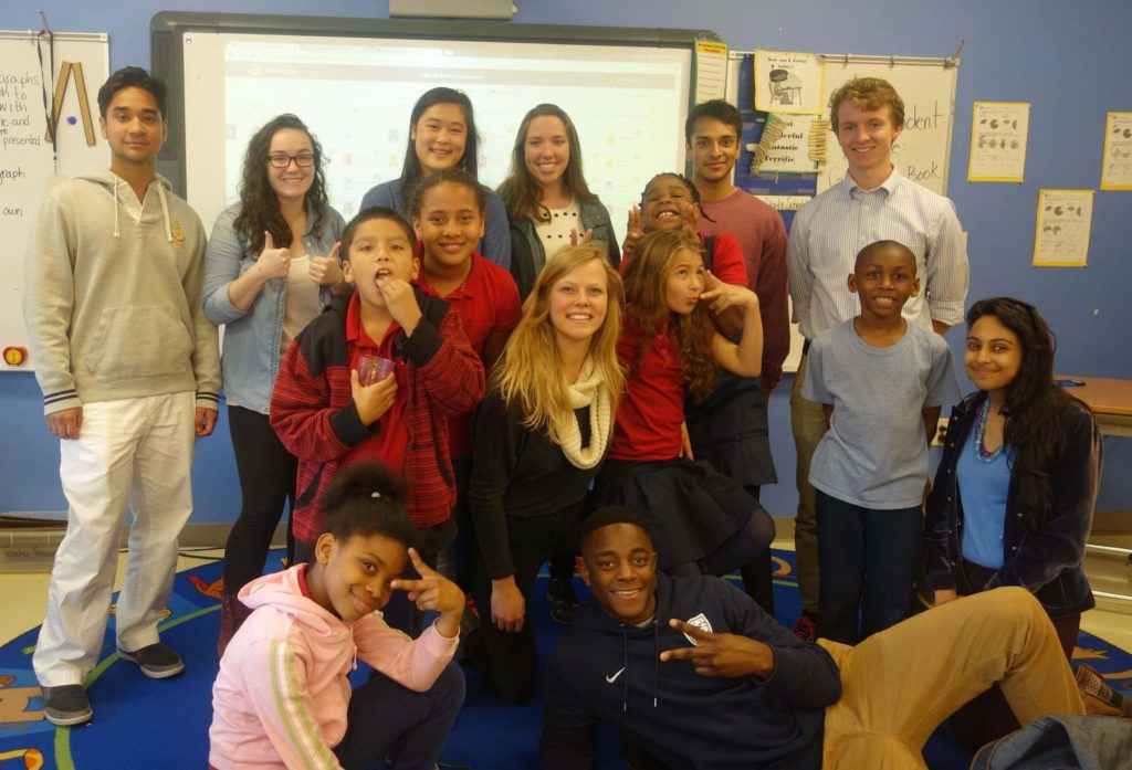 Georgetown student tutors and DC Public School students with the DC STEM program gather together in the classroom for a group photo.