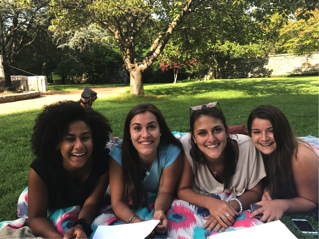 Four FOCI participants lay on a picnic blanket shoulder-to-shoulder, smiling.