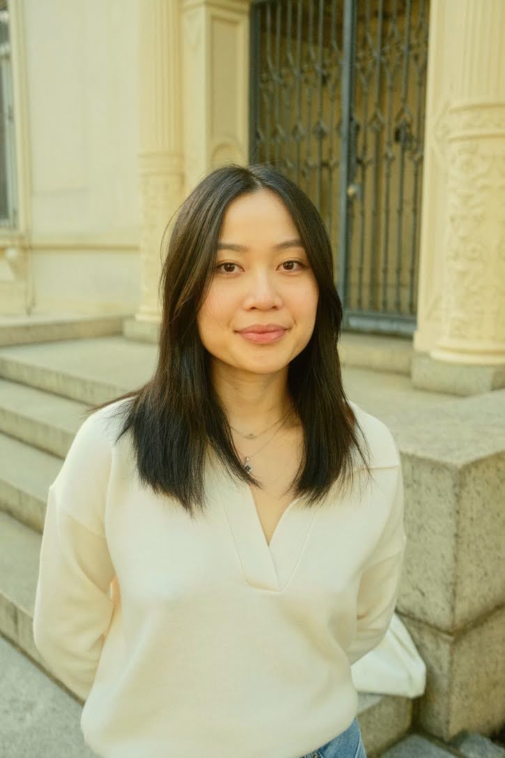 Asian woman with long dark hair wearing a white blouse looking at the camera