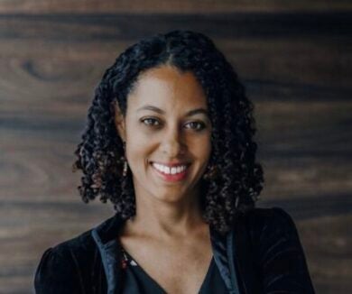 woman with black curly hair smiling at camera