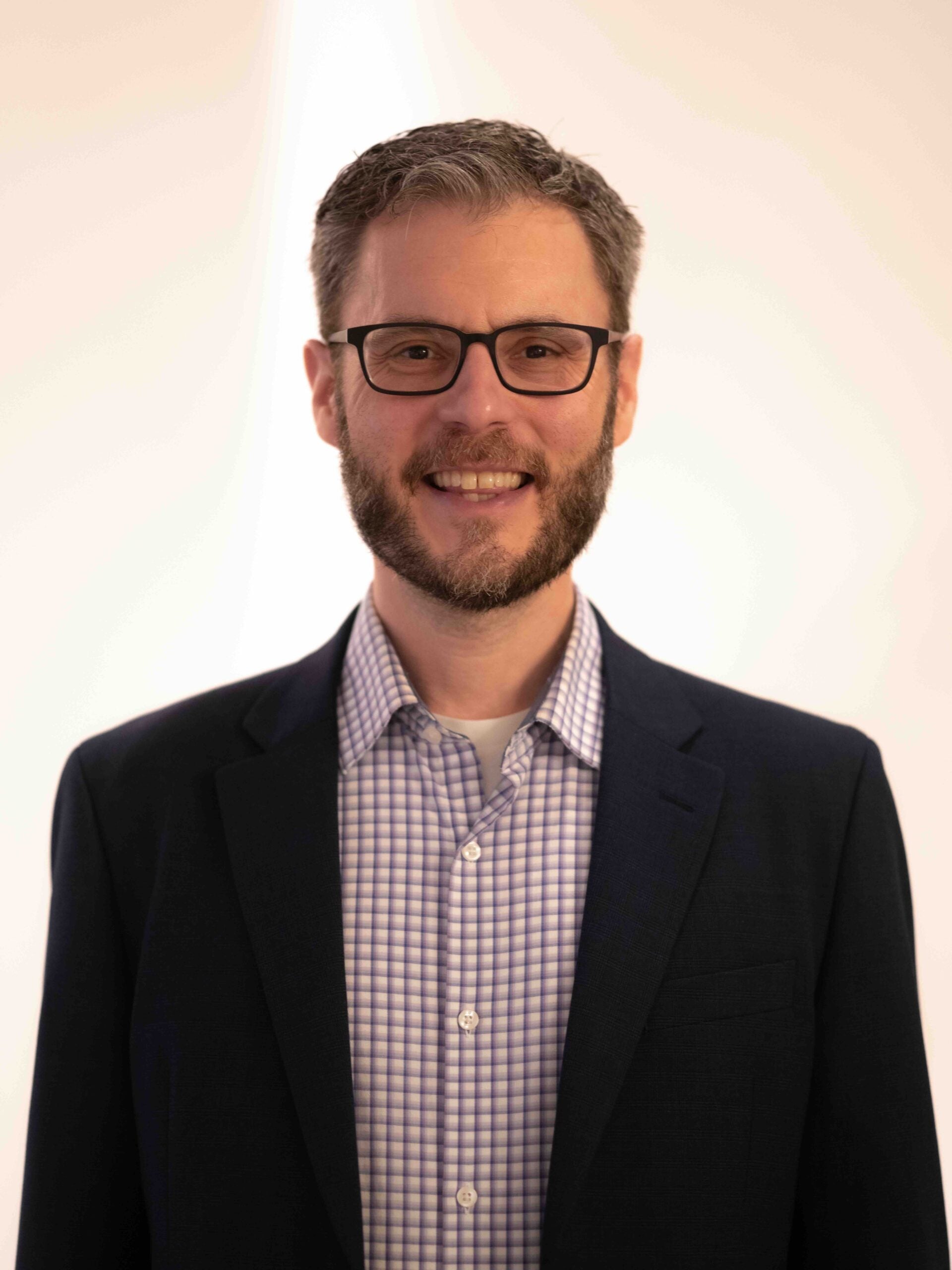 man with short hair wearing glasses smiling at camera