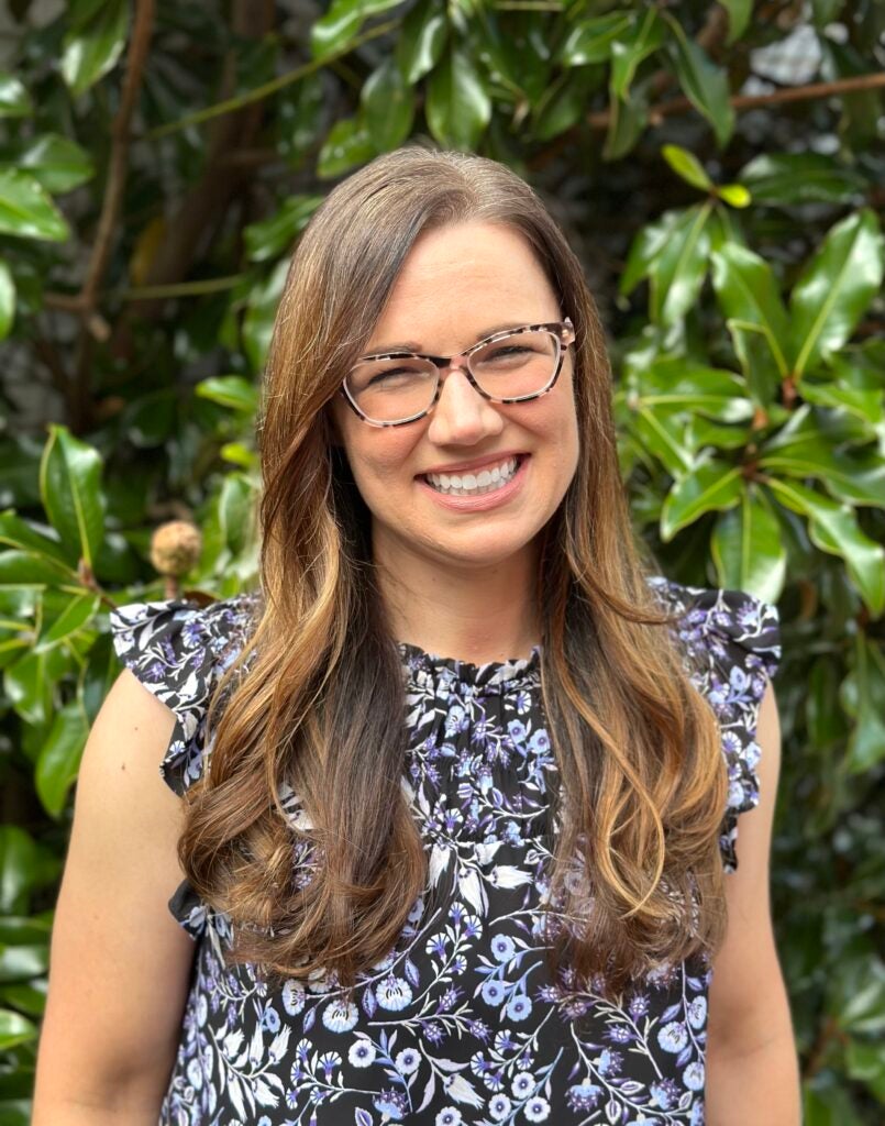 woman wearing glasses smiling at the camera