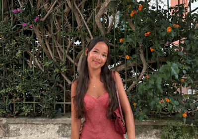 woman with long straight dark hair wearing a pink dress smiling at camera