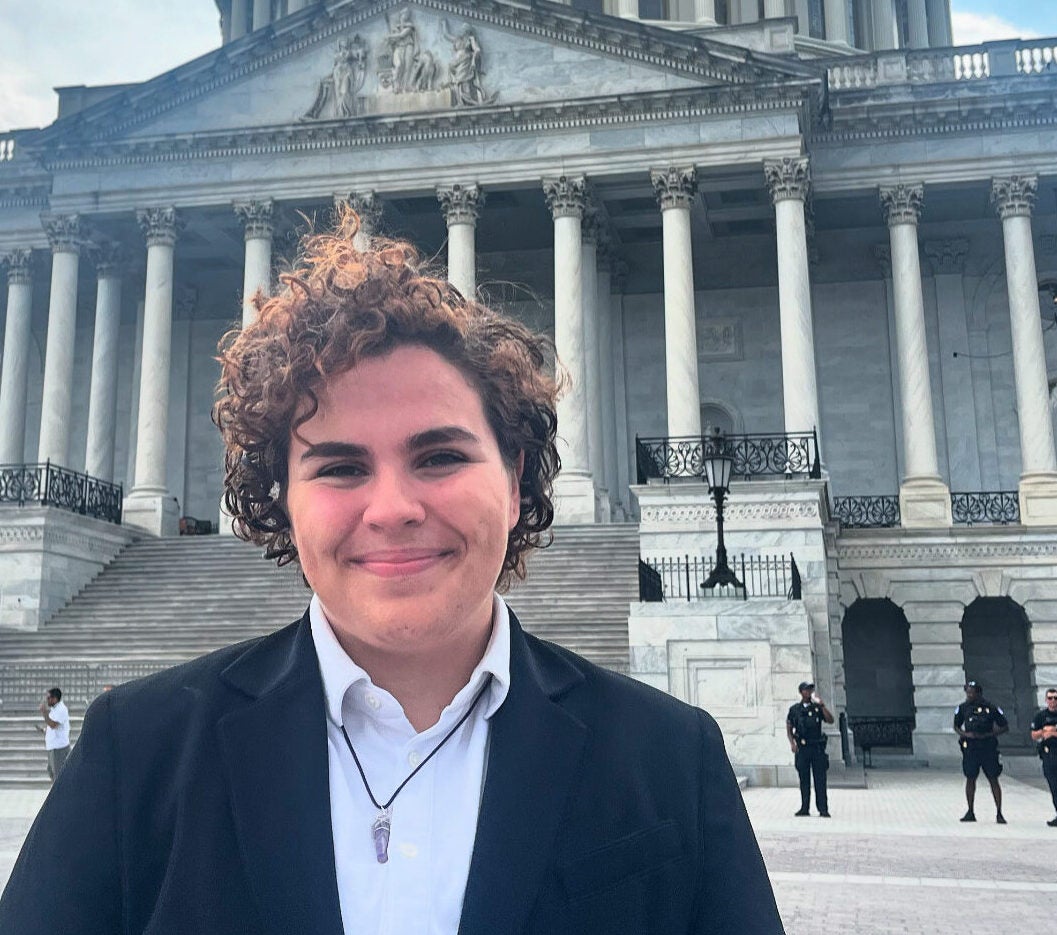 person wearing a blazer with curly hair with Capitol Building in the background