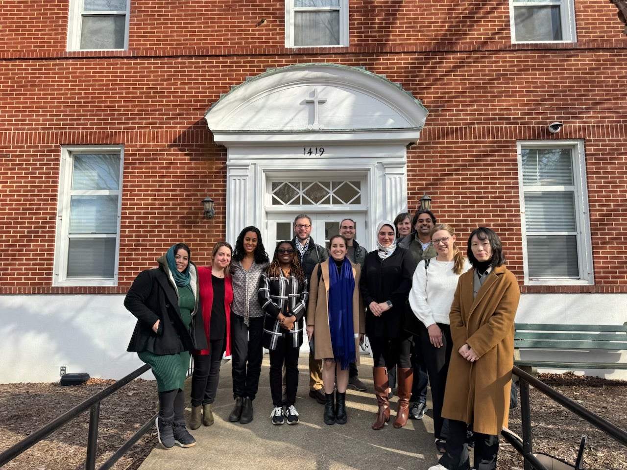 group of diverse people standing in front of a red brick building