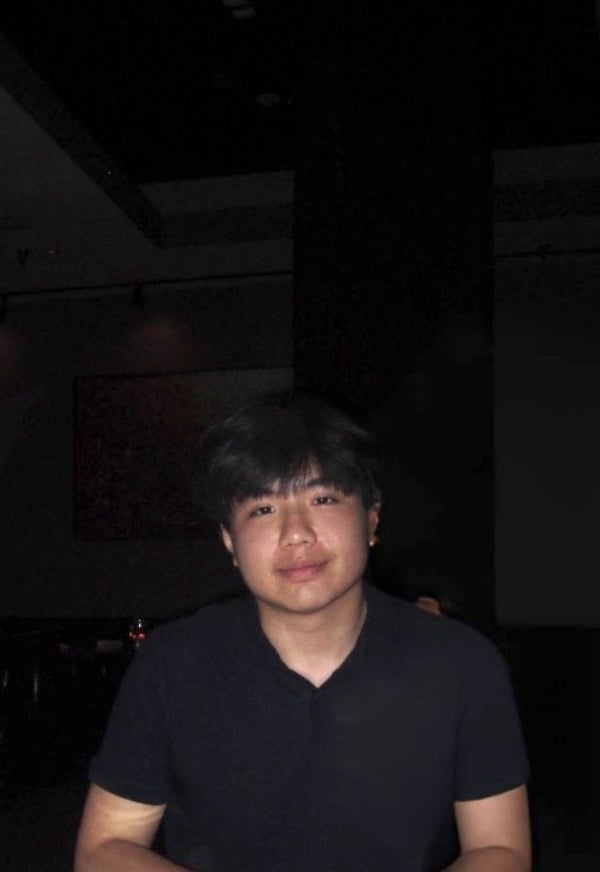 man with dark hair with a very ark background