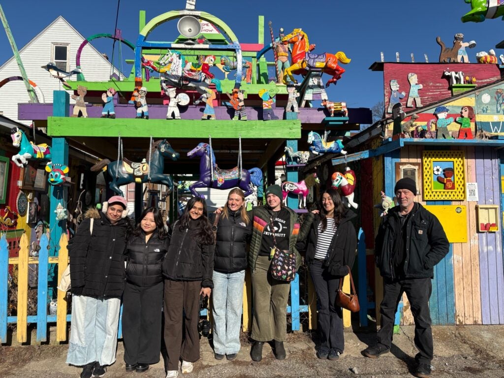 students standing in front of a colorful art sculpture