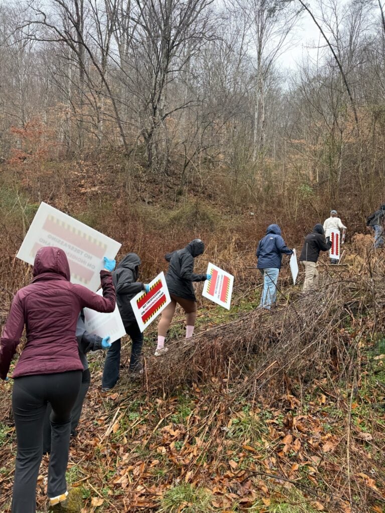 students walking up a hill in the rain carrying signage